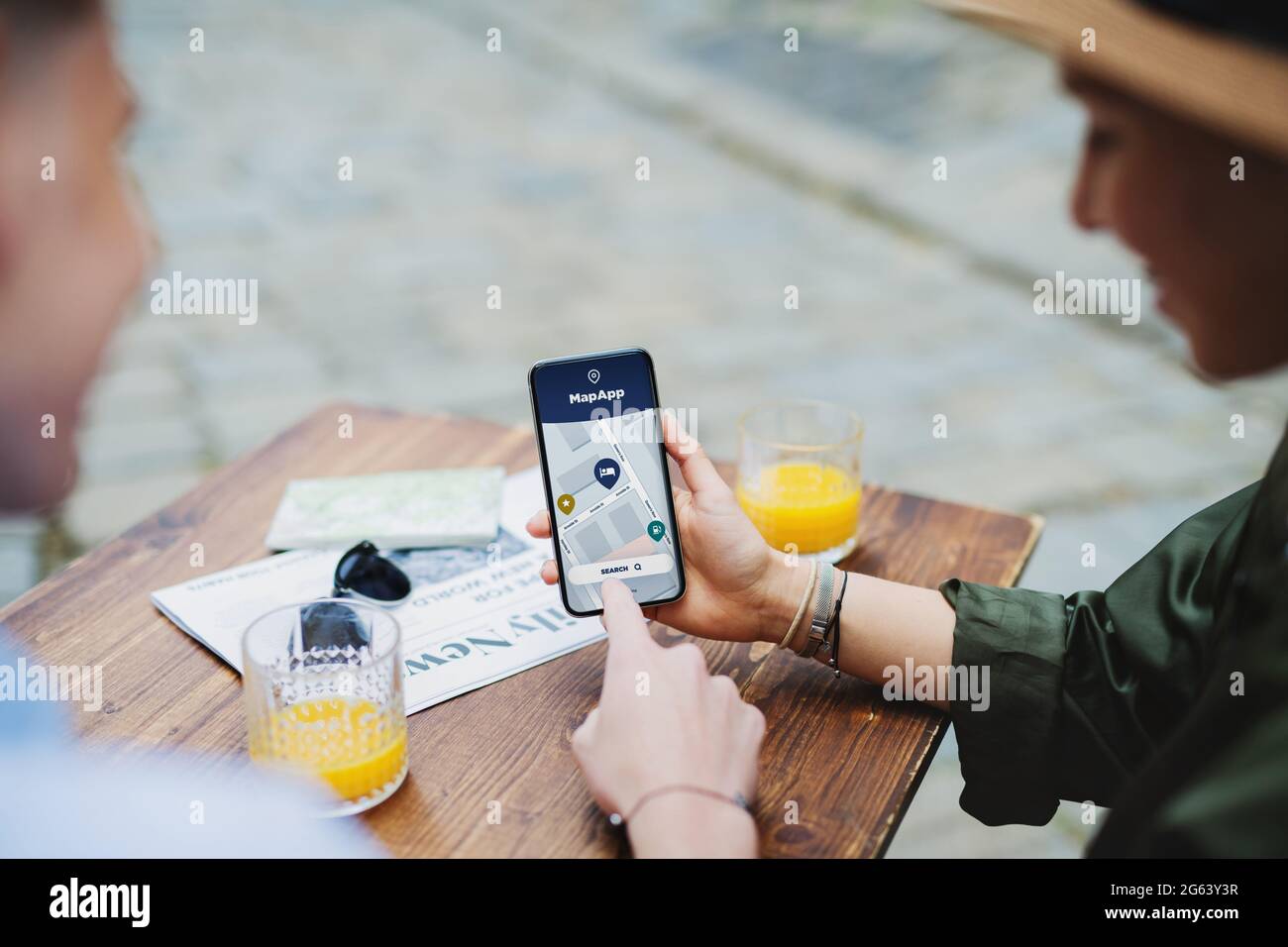 Unrecognizable couple travelers with smartphone looking fat digital map in city on holiday. Stock Photo