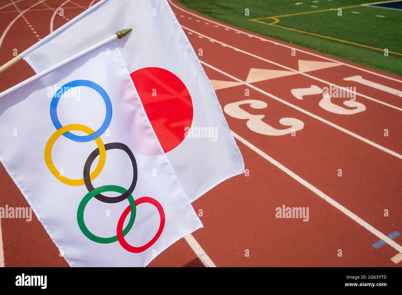 MIAMI, USA - AUGUST, 2019: An Olympic and Japanese flag flutter together above a red athletics track Stock Photo