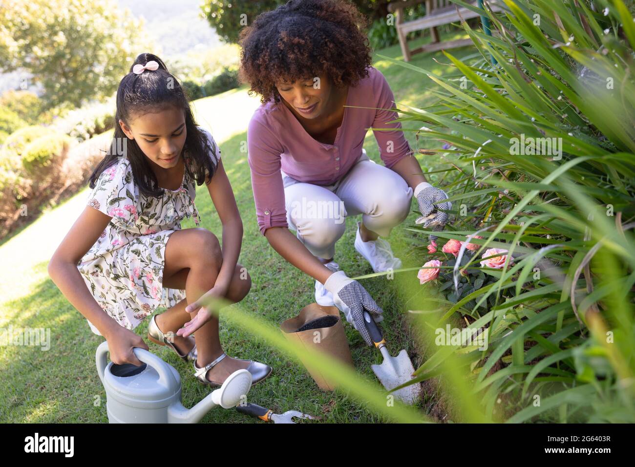 Happy african american mother with daughter outdoors, gardening on sunny day Stock Photo