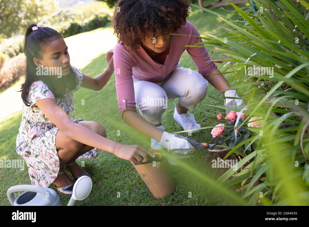 Happy african american mother with daughter outdoors, gardening on sunny day Stock Photo