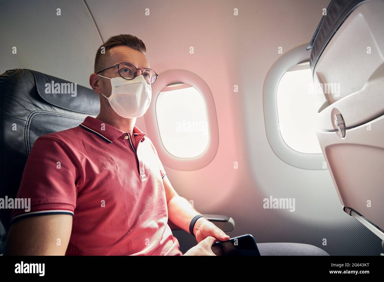 Portrait of passenger with protective face mask in airplane. Themes traveling in new normal and personal protection during pandemic covid-19. Stock Photo