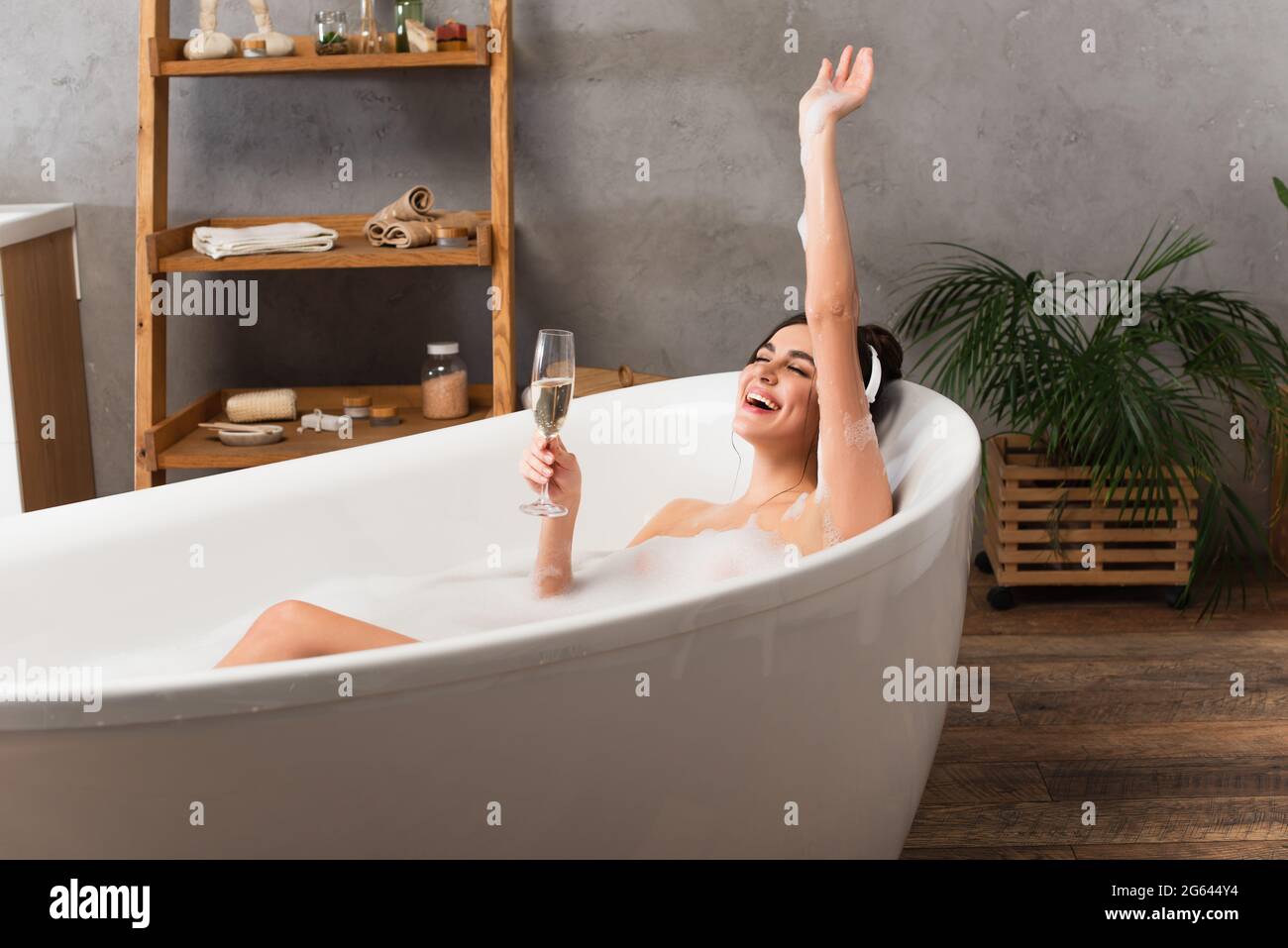 happy woman in headphones listening music and holding glass of