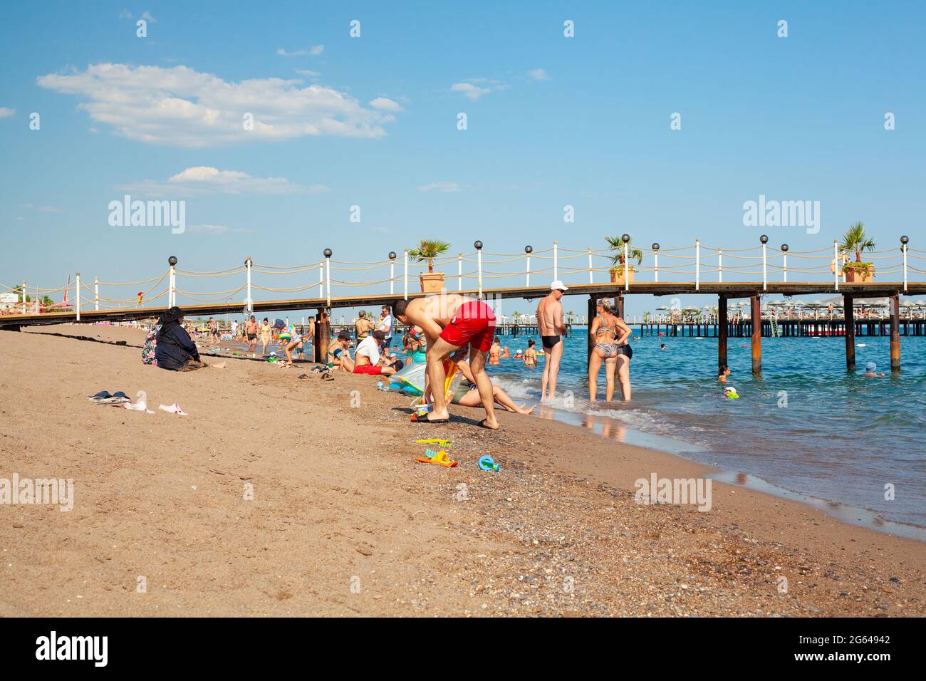 Antalya, Turkey-June 29, 2021: Beach-goers sunbathing, swimming or doing other activites on the beach in summer in Antalya during coronavirus pandemic. Stock Photo