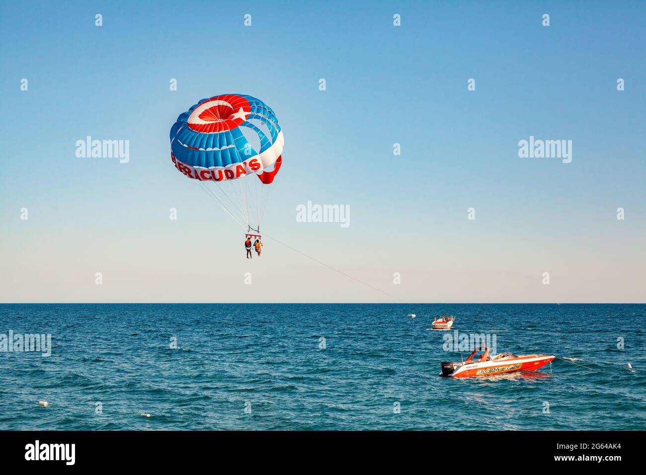 Antalya, Turkey-June 30, 2021: Tourists flying on a parachute behind a boat on a summer holiday. Tourists parasailing on summer vacation during corona Stock Photo