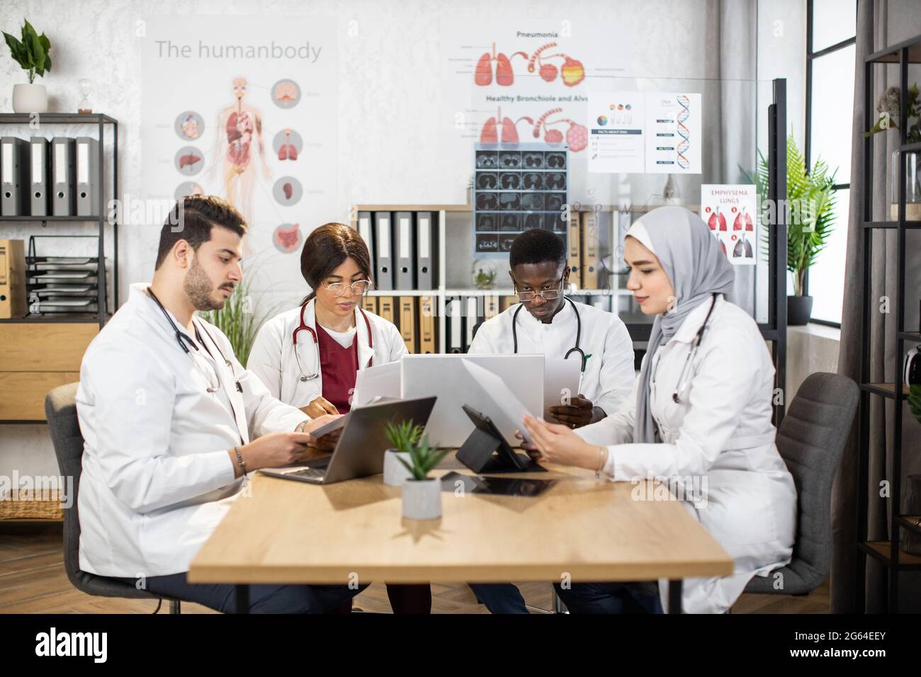 Focused multicultural doctors working with documents and gadgets at ...