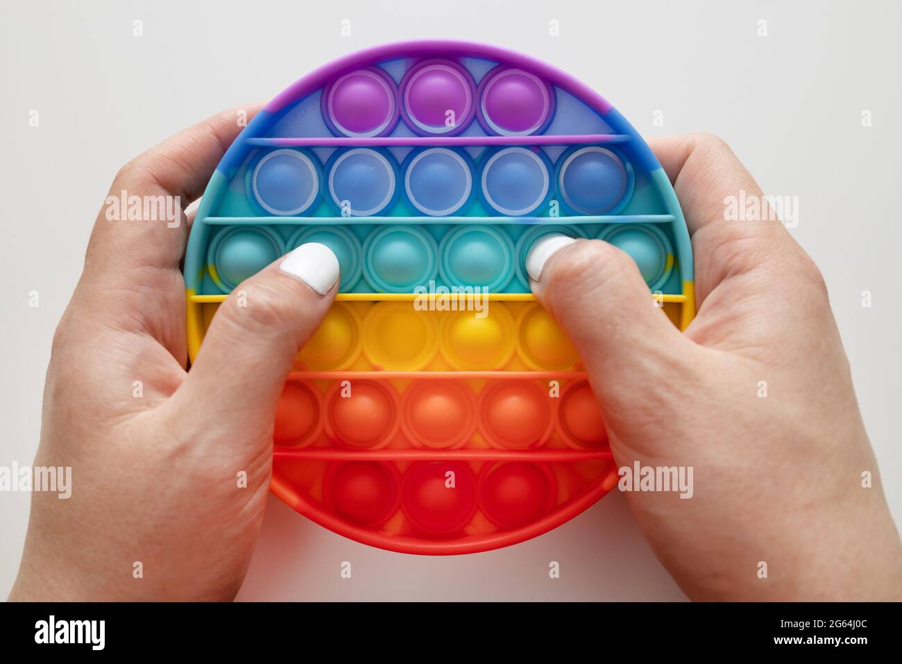 Rainbow sensory fidget isolated in the hand on white background. New trendy silicone toy. Stock Photo