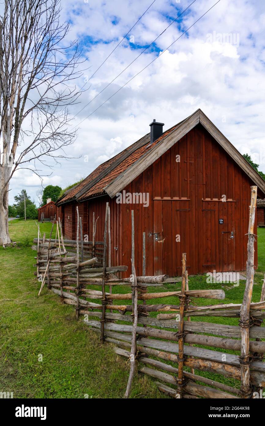 Gamla Uppsala, Sweden - 24 June, 2021: idyllic red shed in the Swedish countryside with an old wooden fence in the foreground Stock Photo