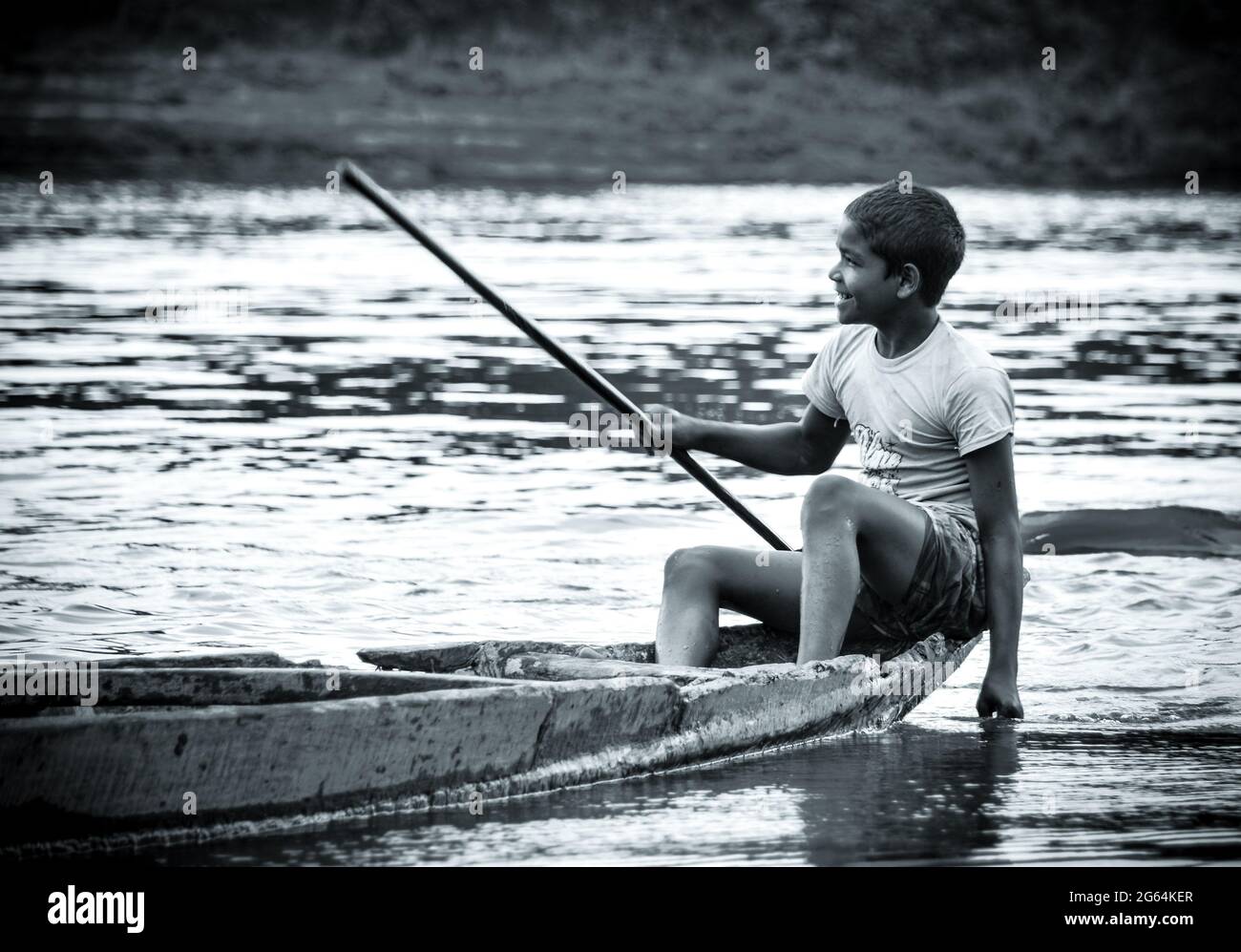 A smiling kid driving boat on a river in Sylhet, Bangladesh. Poor happy boy smiling, Stock Photo