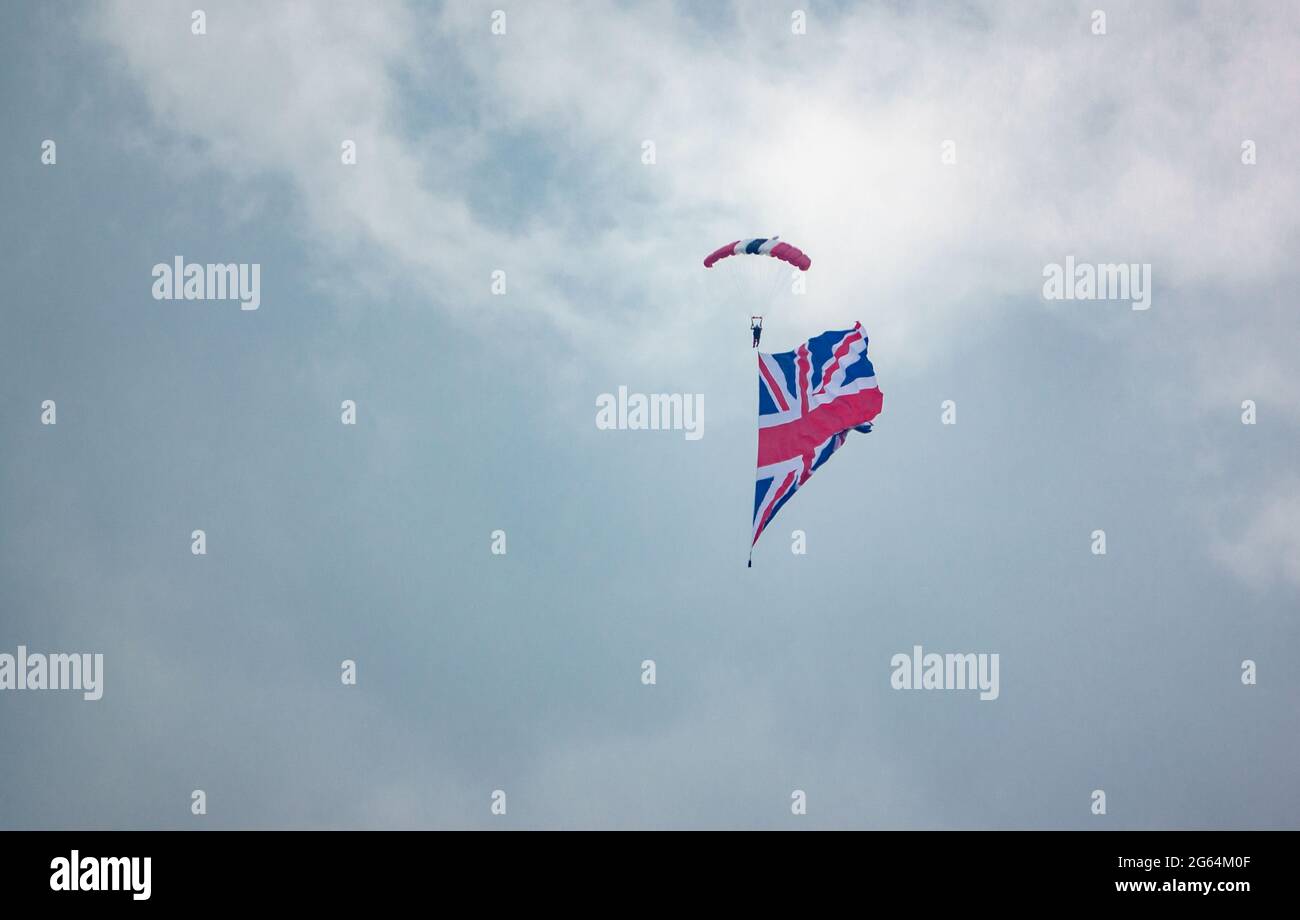 Red Devil's parachutist display team member descends with a huge union flag in tow Stock Photo