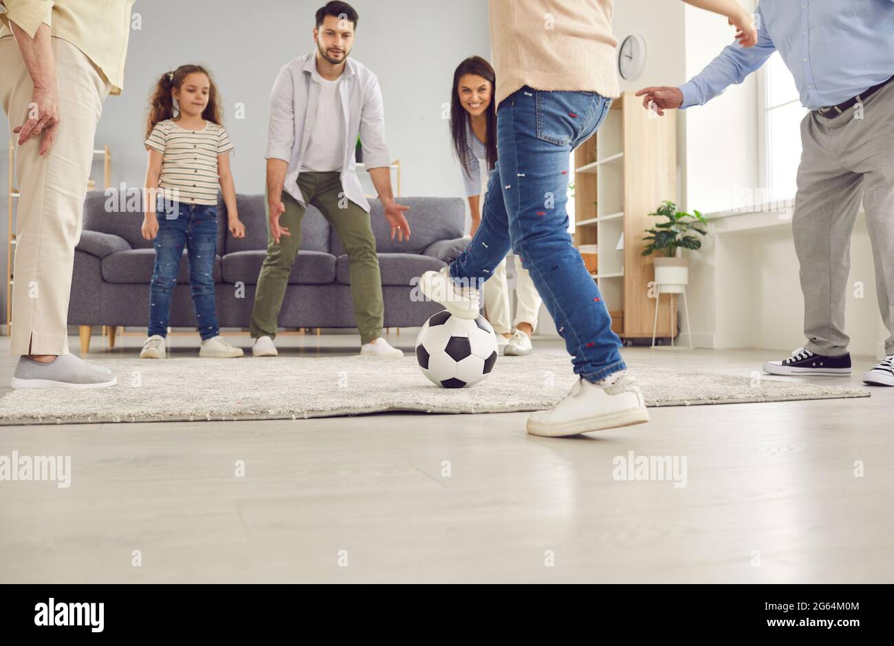 Happy mum, dad, grandma, grandpa and children playing football and having fun at home Stock Photo