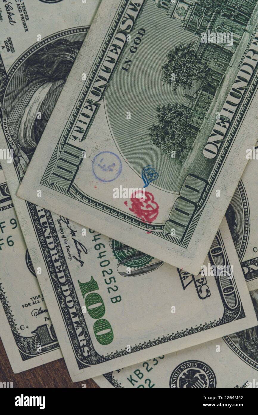Flat lay American cash banknote 100 dollars bill marked by inked symbols. Red and blue ink strange symbols stamped on banknote. US dollar money backgr Stock Photo