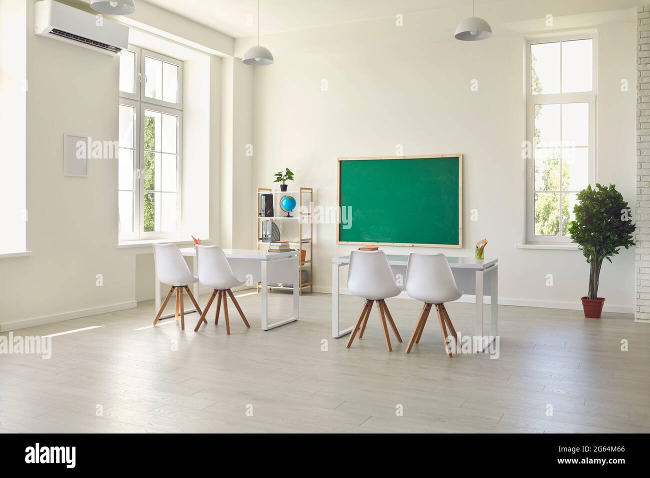 Modern empty classroom interior with desks, chairs and chalkboard. Light schoolroom with comfy furniture and big windows Stock Photo