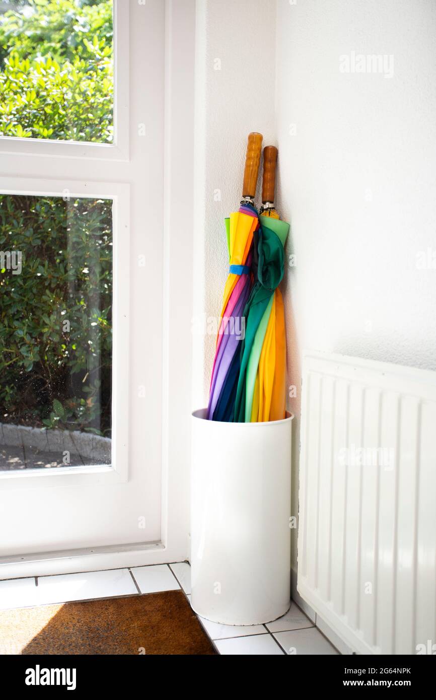 Umbrella in holder rainbow colored in white hallway, modern design in bright house next to door