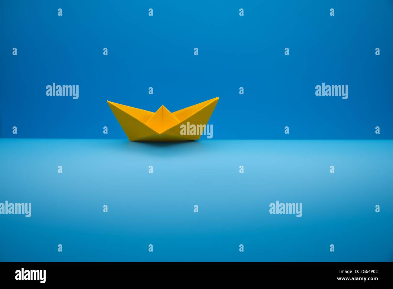 Paper boat on a wave against a blue gradient background Stock Photo