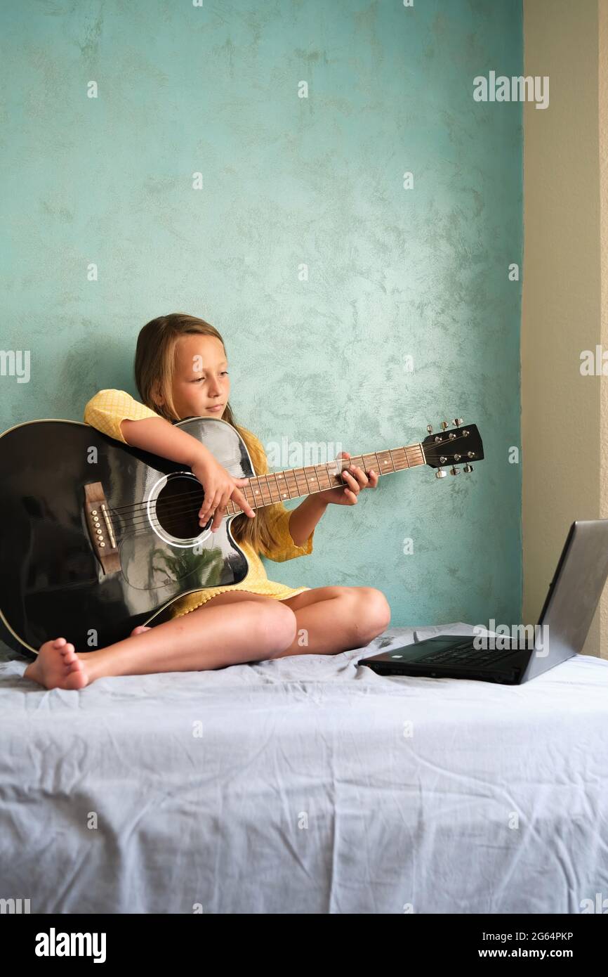 a little girl is learning to play the guitar Stock Photo