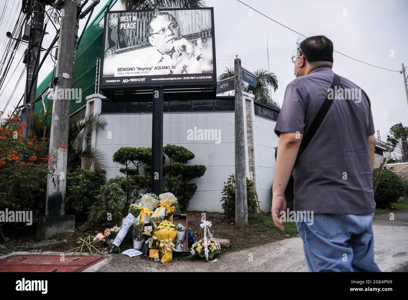 A man looks at a digital screen displaying the face of former Philippine President Benigno Aquino III who died at the age of 61 near his house in Manila, Philippines. Stock Photo