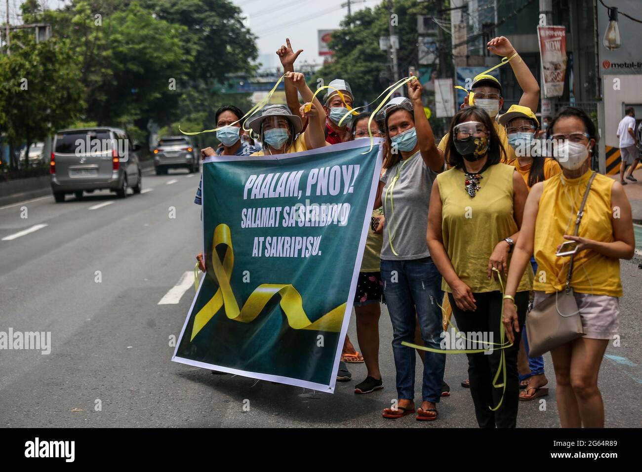 Supporters carry signs as they gather beside the motorcade of former Philippine President Benigno Aquino III before his burial in Quezon City, Philippines. Stock Photo