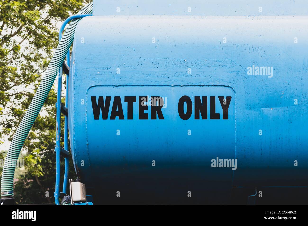 The words 'water only' written on the side of a blue water truck used for construction sites. Hose on side of truck. Stock Photo