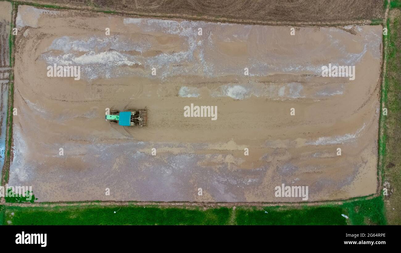 Aerial Top-down view of a tractor ploughing muddy field Stock Photo
