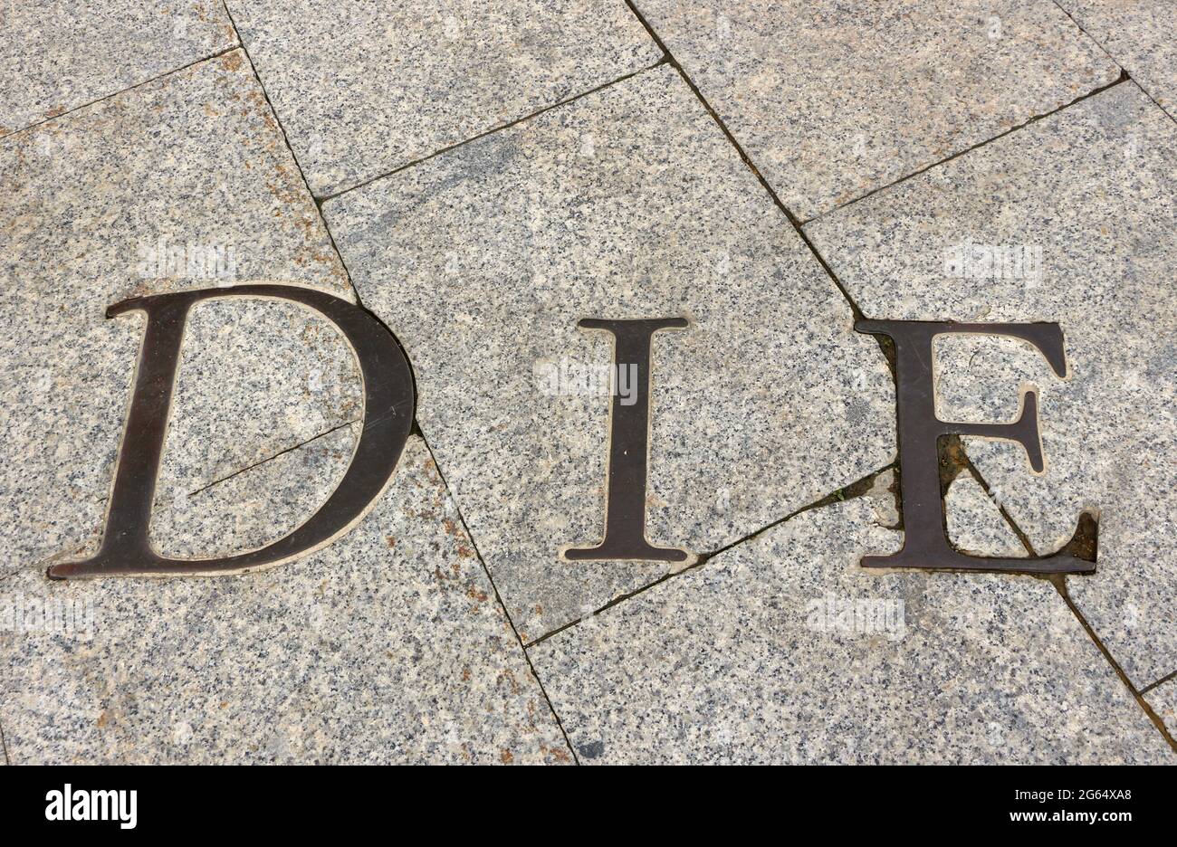 Bronze lettering inlaid into paving with the word DIE Stock Photo - Alamy