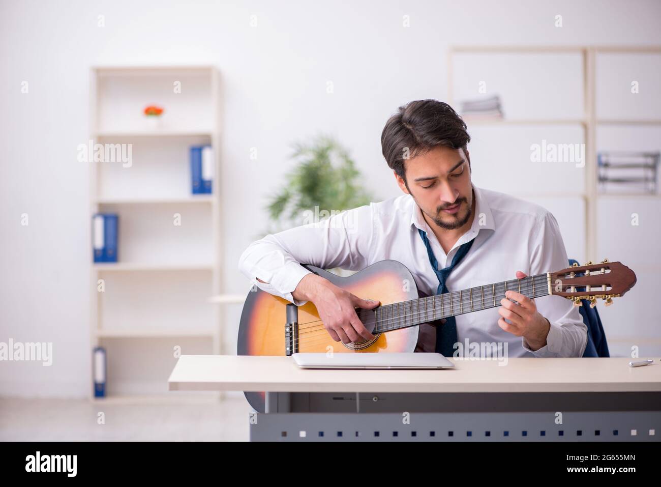 Young businessman employee playing guitar at workplace Stock Photo Alamy