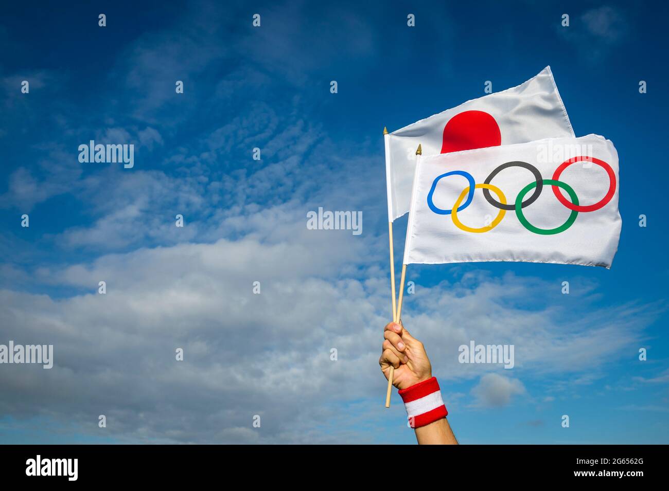 RIO DE JANEIRO - CIRCA MARCH, 2016: An Olympic and Japanese flag held in the hand of an athlete wearing a red and white wristband flutter together in Stock Photo