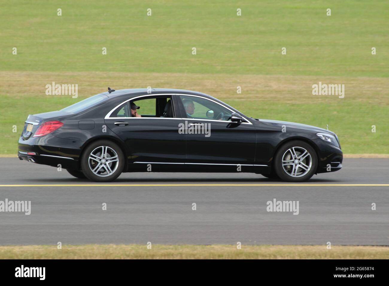 A chauffeur-driven Mercedes-Benz motoring along the taxiway at Prestwick International Airport in Ayrshire, Scotland. Stock Photo