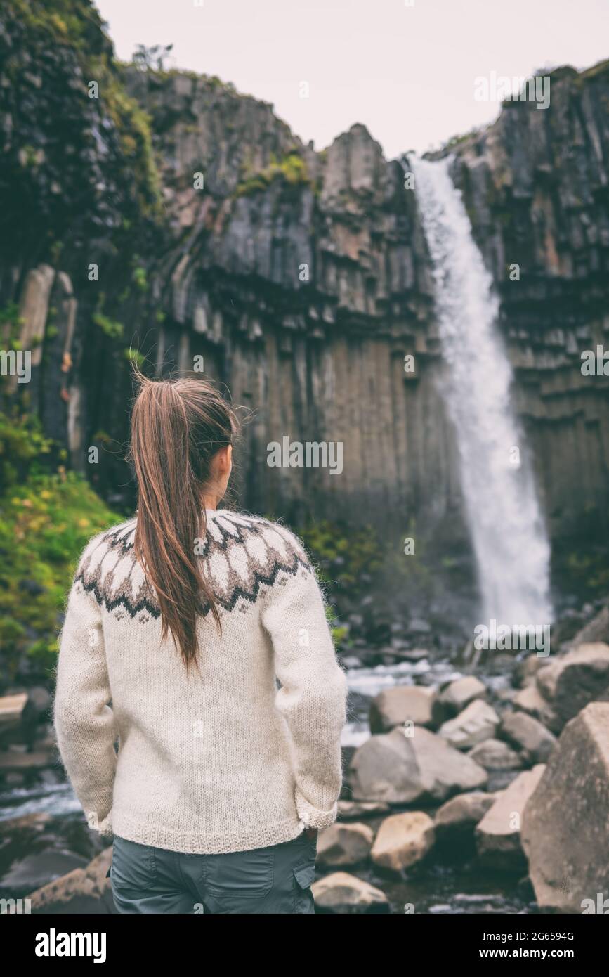 Iceland. Woman enjoying majestic Svartifoss waterfall. Female is visiting famous tourist attraction of Iceland. Spectacular natural landmark on Stock Photo