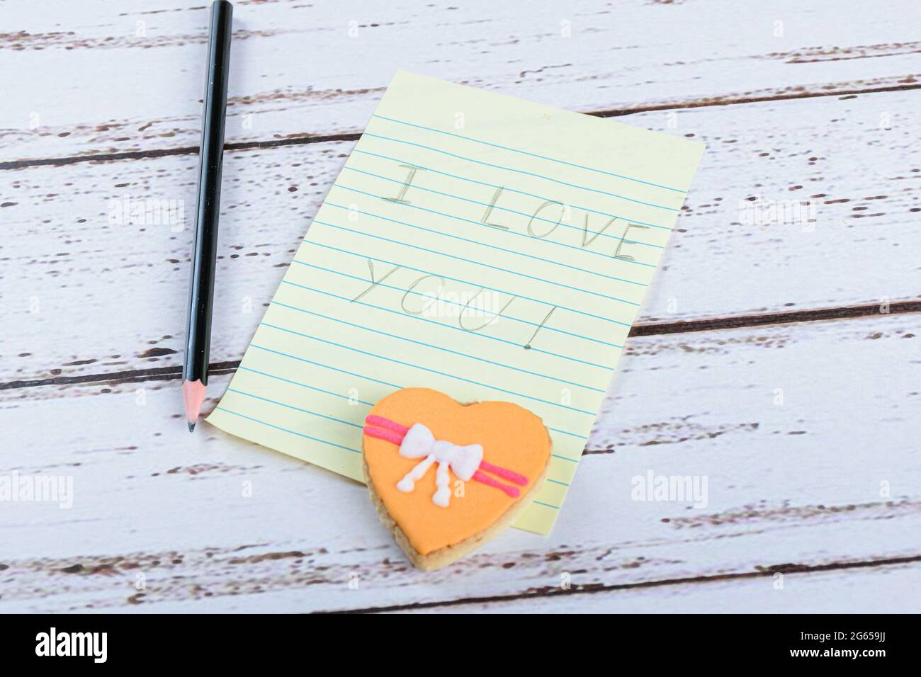 Notepad written I love you next to a pencil and a cookie. Stock Photo