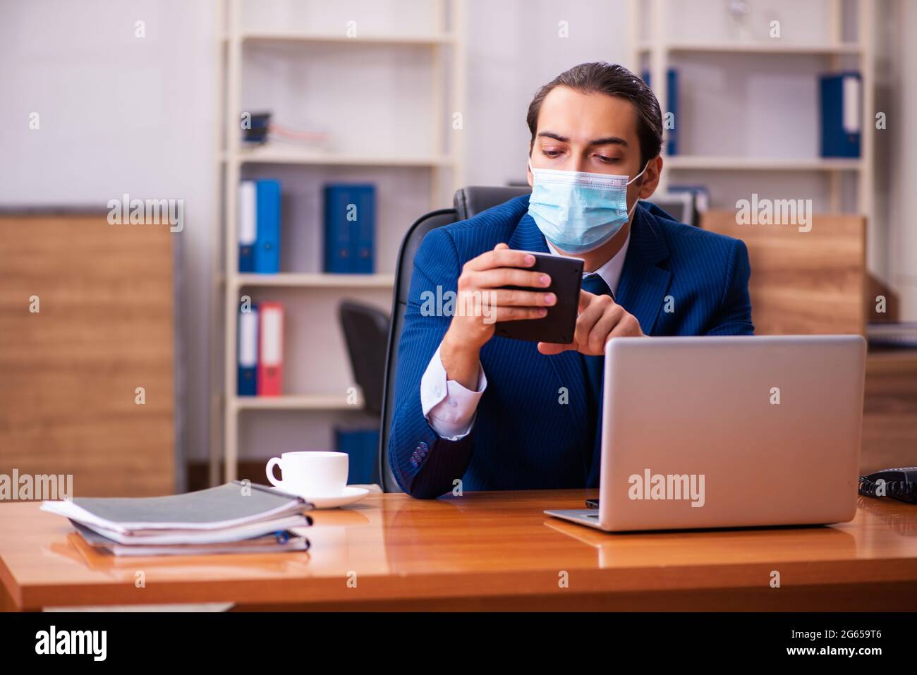 Young employee working in the office wearing mask Stock Photo - Alamy