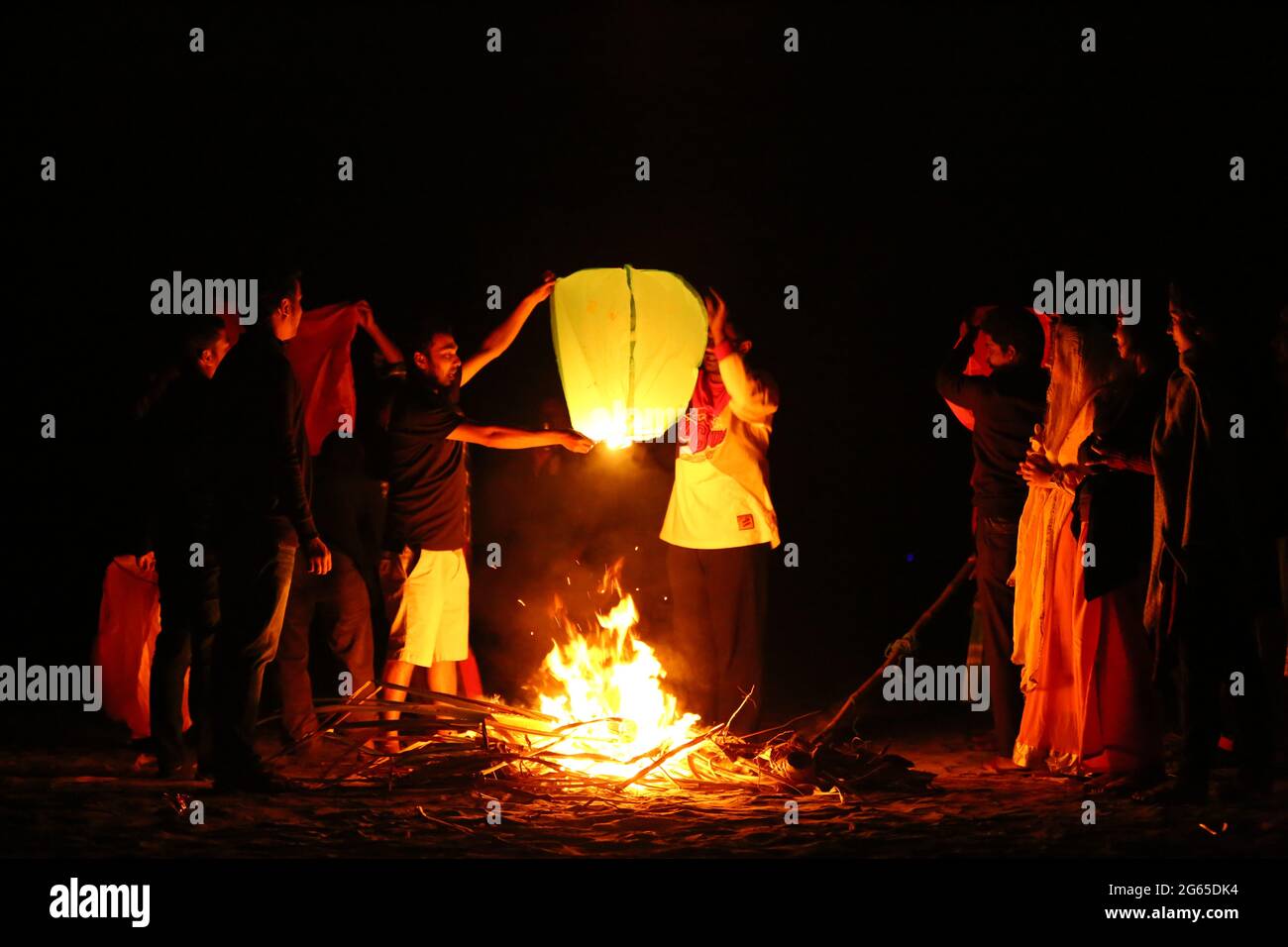 A Buddhist monk with his disciples trying to fly a paper lantern at Ujani Para Buddhist Temple in Bandarban, Bangladesh. Stock Photo