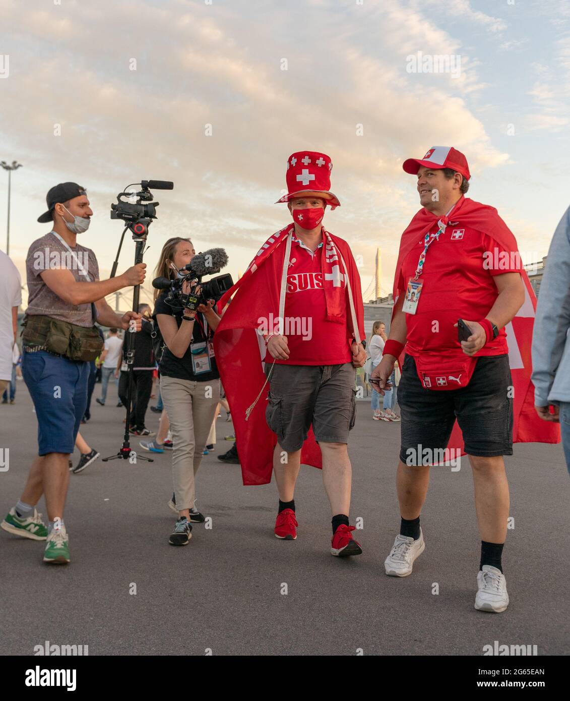 Swiss football fans dressed in colorful red Suisse outfits, face mask, are interviewed  after UEFA EURO 2020 quarterfinal game, St Petersburg, Russia Stock Photo