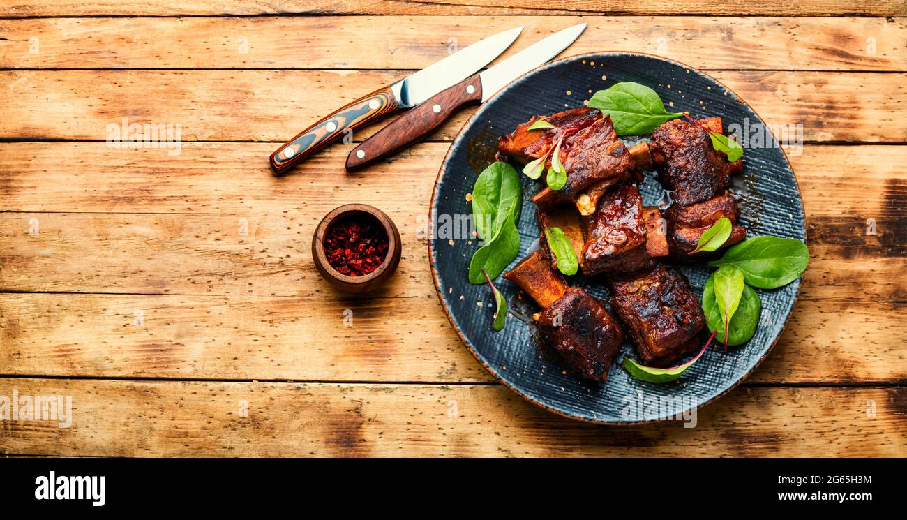 Spicy barbecue beef ribs with herb on rustic wooden table.BBQ beef rib.Space for text Stock Photo