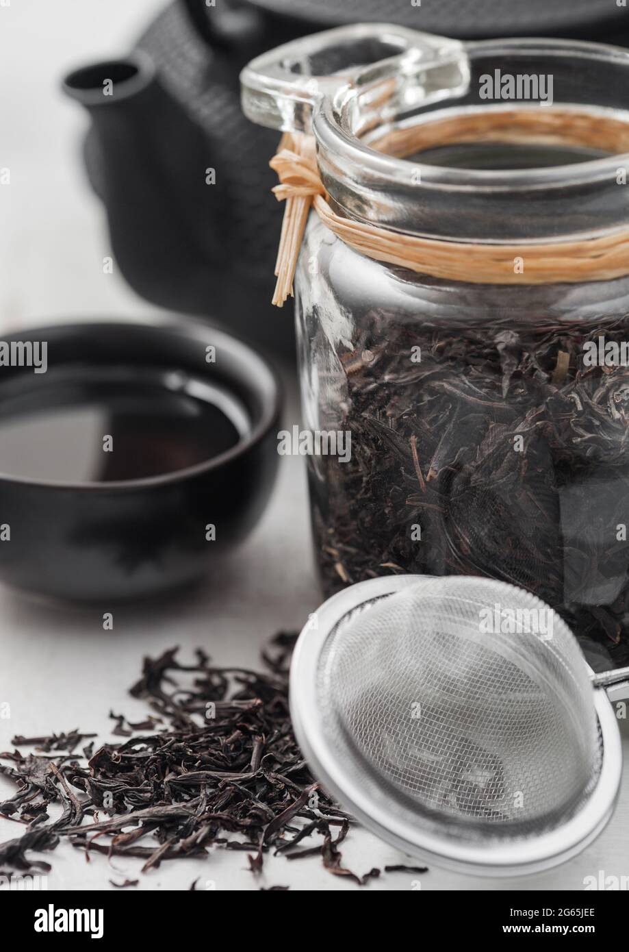 https://c8.alamy.com/comp/2G65JEE/glass-jar-of-black-loose-organic-tea-with-teapot-and-cup-with-tea-strainer-infuser-on-light-background-2G65JEE.jpg
