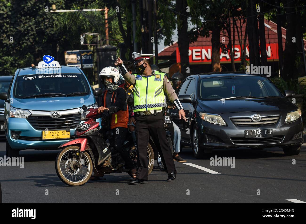 (210703) -- JAKARTA, July 3, 2021 (Xinhua) -- A police officer asks a man without a proper face cover to pull over to the side of the road in Jakarta, Indonesia, July 3, 2021. The Indonesian government has decided to deploy 53,000 personnel for emergency community activity restrictions (locally known as PPKM) to be imposed in Java and Bali from July 3 to 20, a senior police officer said on Friday. (Xinhua/Agung Kuncahya B.) Stock Photo