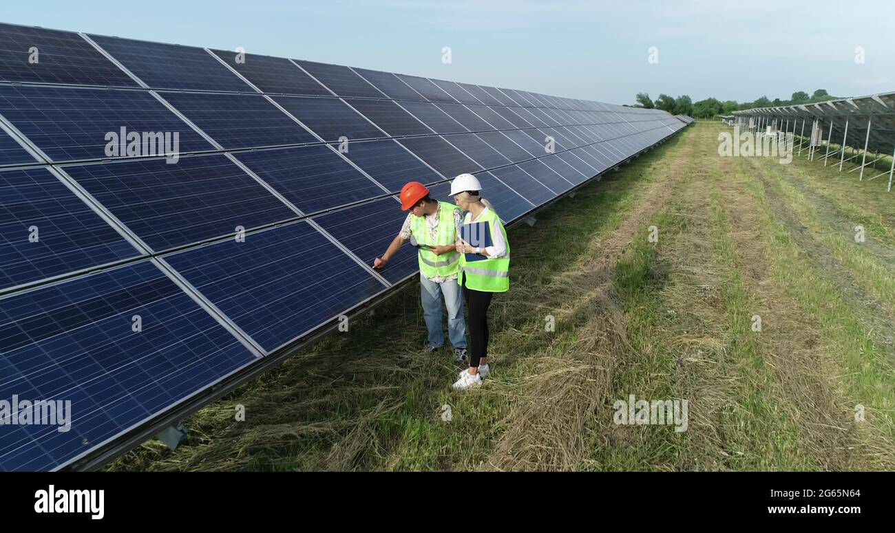 Two solar power engineers working on a solar farm. Drone shot. Stock Photo