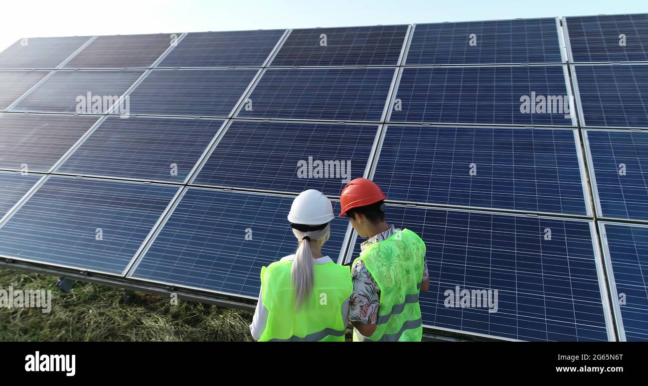 Two solar power engineers working on a solar farm. Drone shot. Stock Photo
