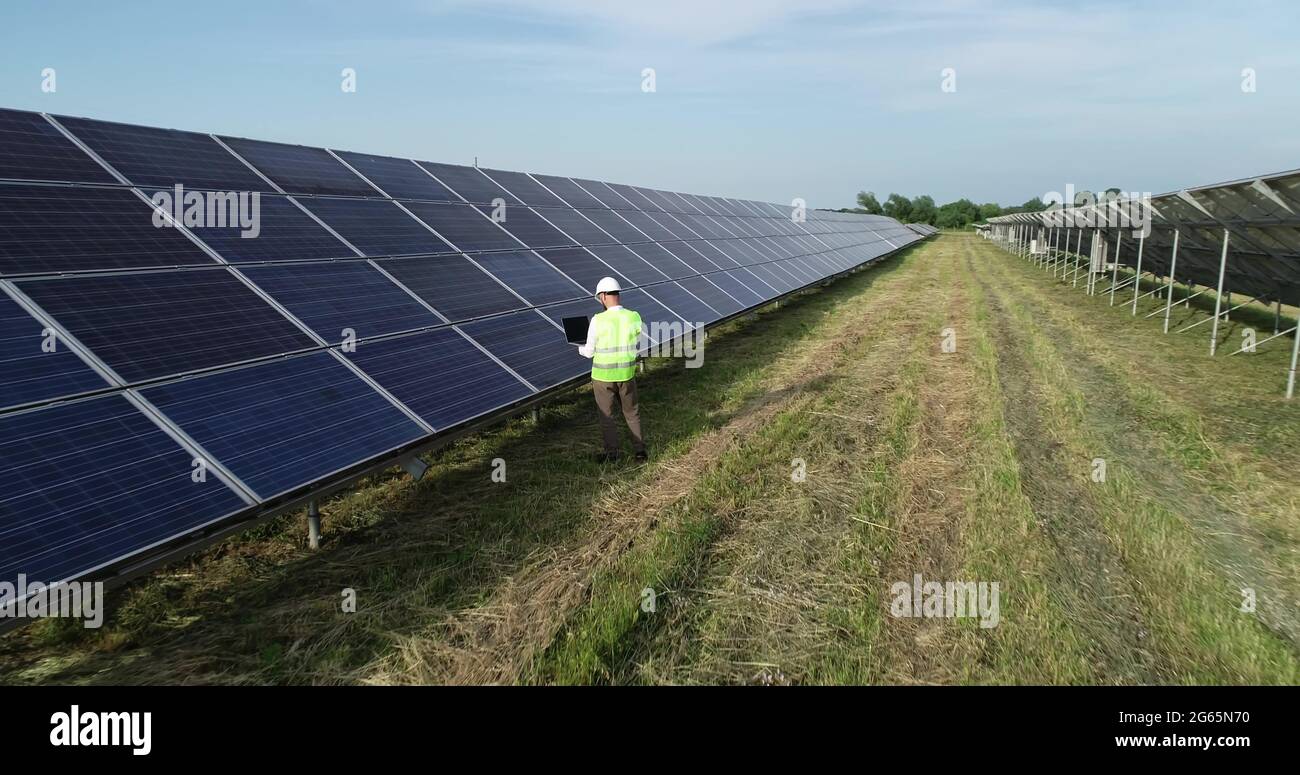 Solar power engineer working on a solar farm. Drone shot Stock Photo ...