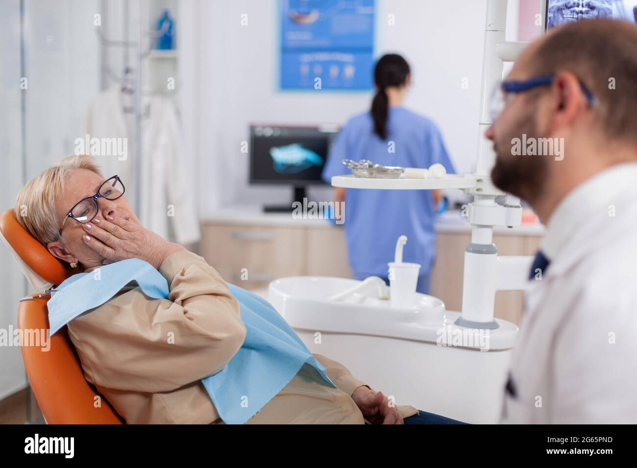Elderly patient waiting diagnostic from dentist doctor sitting on dental clinic chair. Senior woman in healthcare hospital accusing and complaining about tooth. Stock Photo