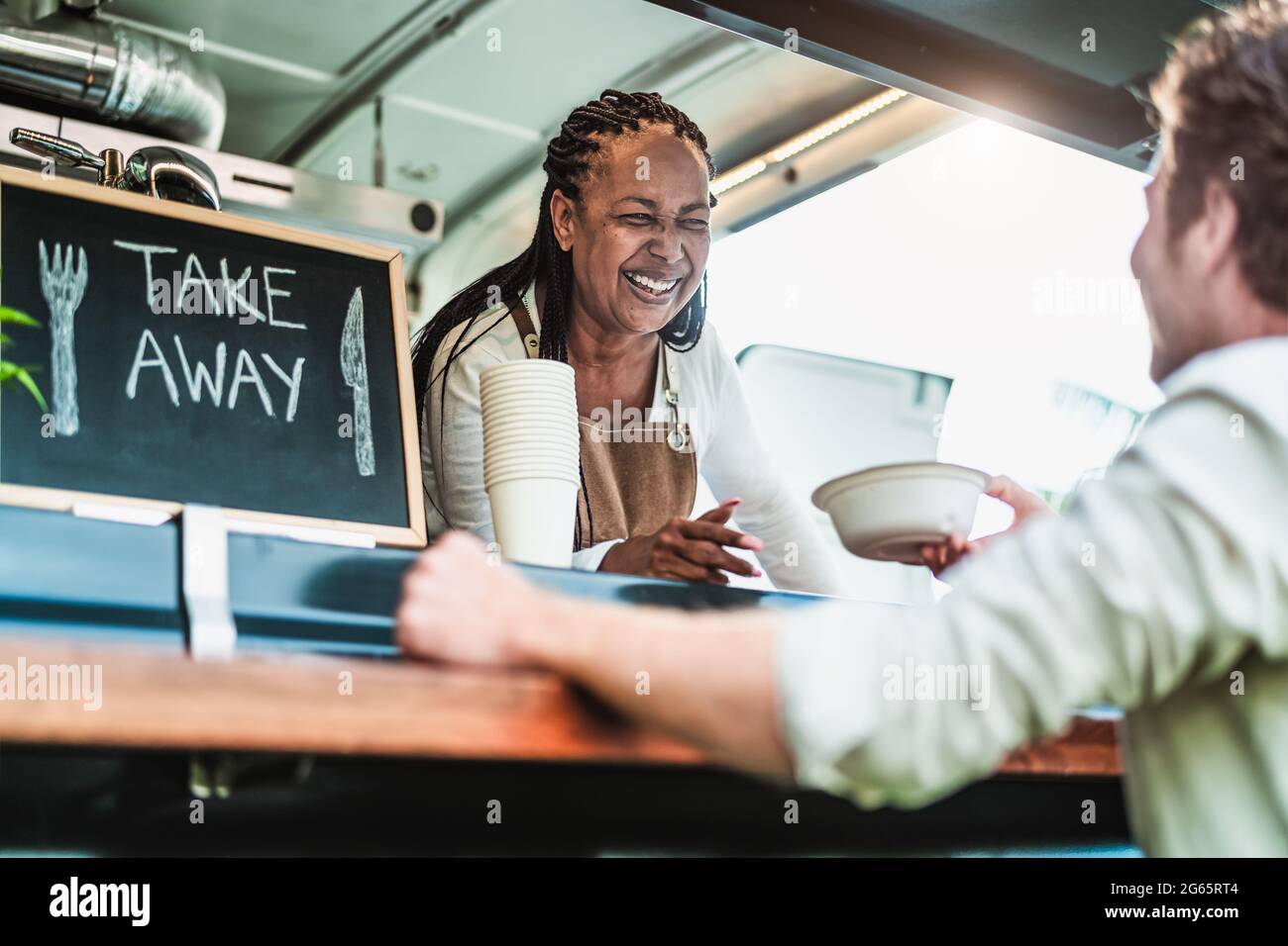 Female food truck owner serving meal to male customer - Modern business and take away concept Stock Photo