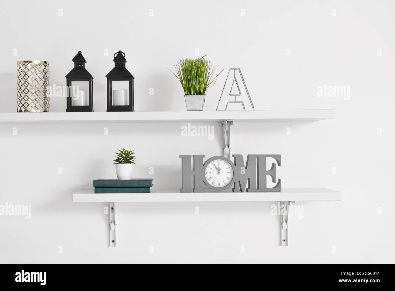 Book shelves with decor hanging on light wall Stock Photo