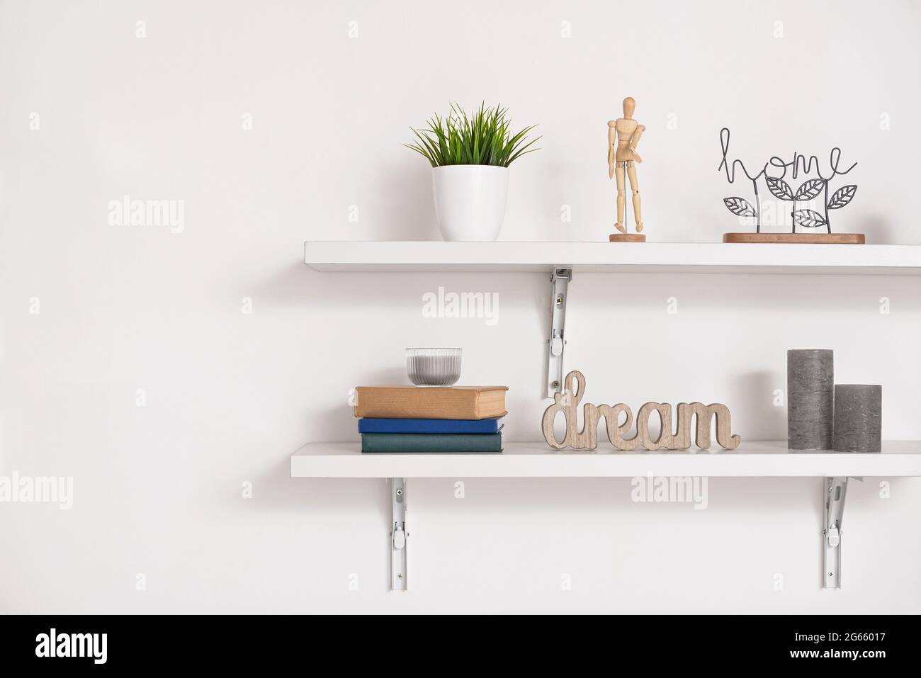 Book shelves with decor hanging on light wall Stock Photo