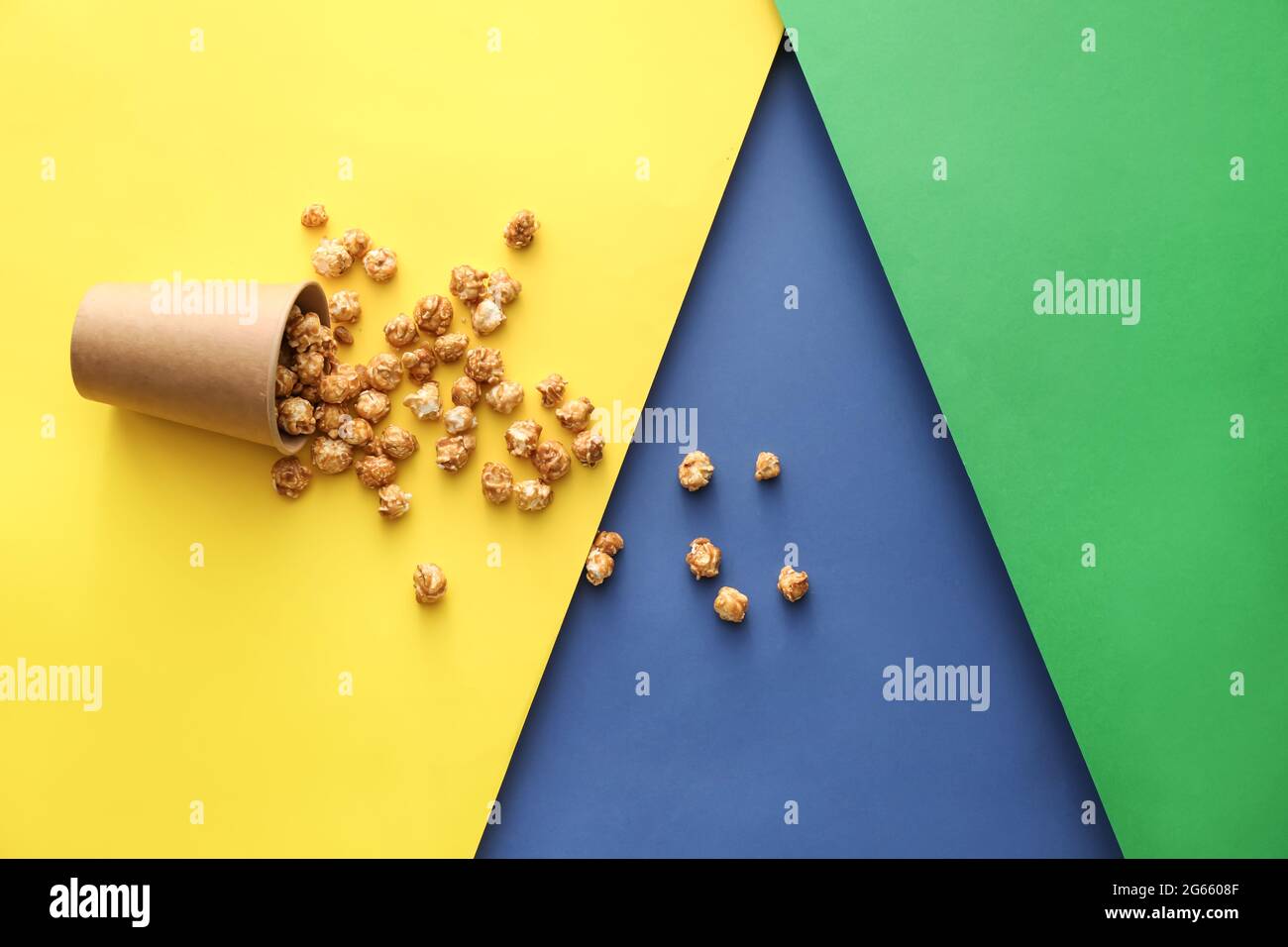 Paper cup with tasty caramel popcorn on color background Stock Photo ...