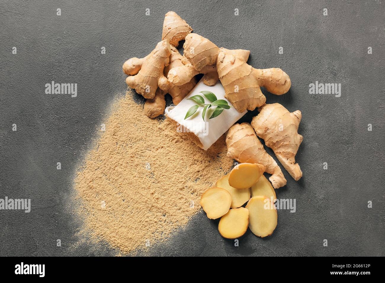 Ginger powder and roots on dark background Stock Photo