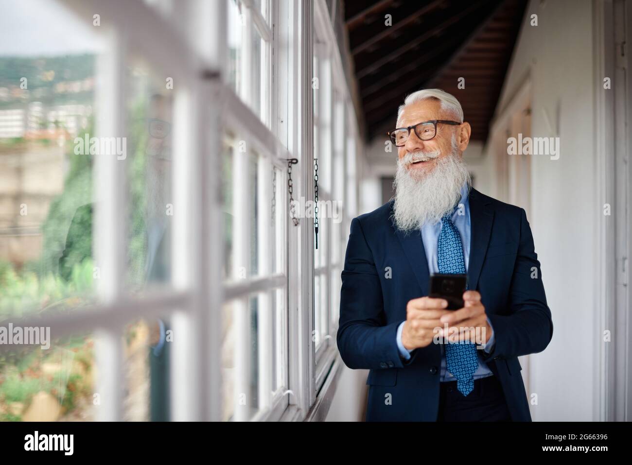 Business hipster senior man using mobile phone inside modern office - Focus on face Stock Photo