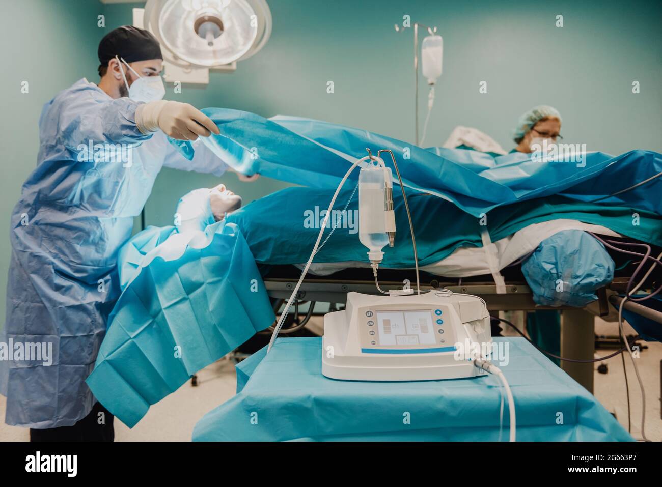 Medical doctors team preparing patient in operating room at hospital - Focus on ultrasonic equipment Stock Photo