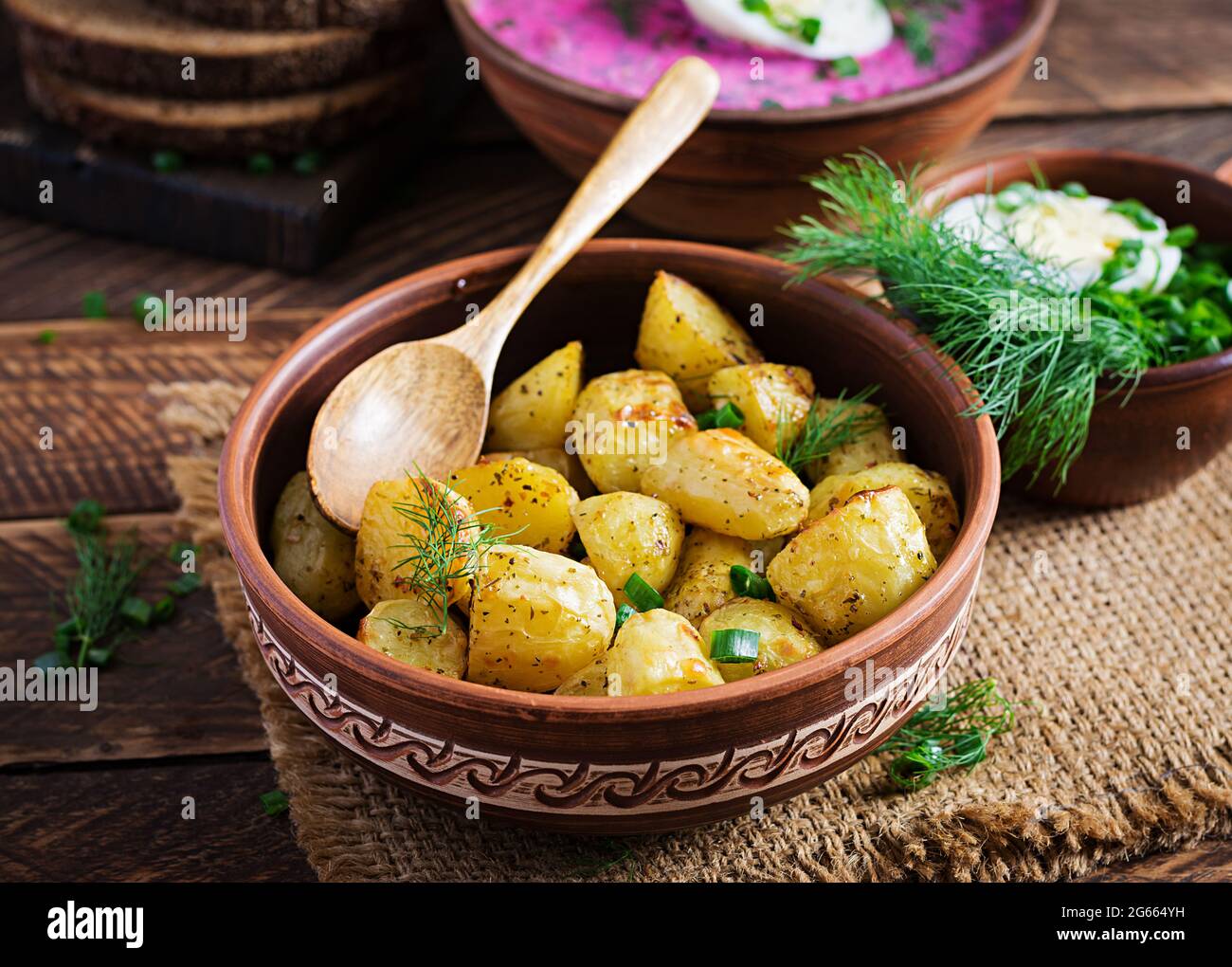 Baked potato wedges in a bowl on wooden table.  Delicious lunch. Stock Photo