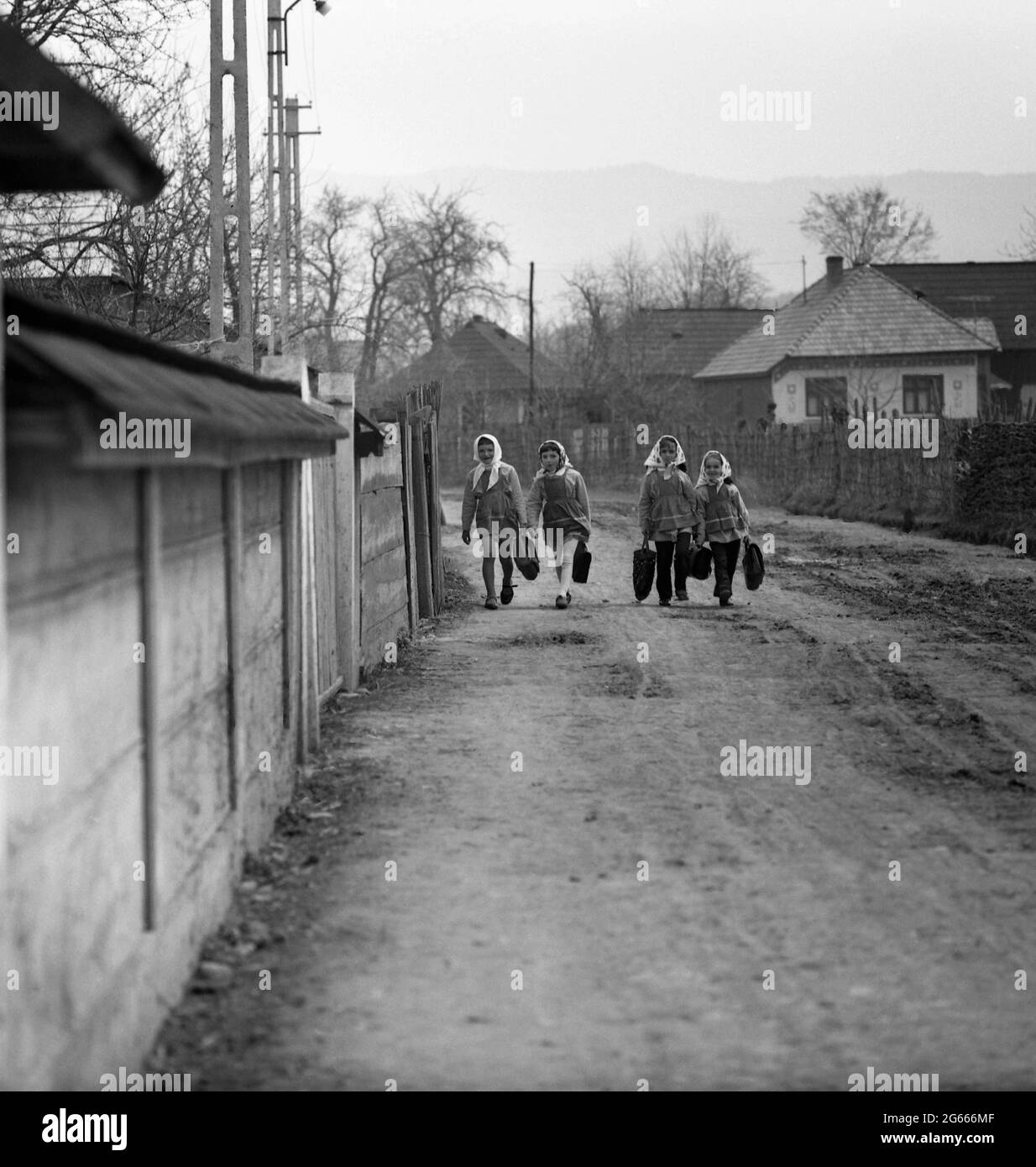 Socialist Republic of Romania, 1975. Group of girls coming from school on the muddy village path. Stock Photo