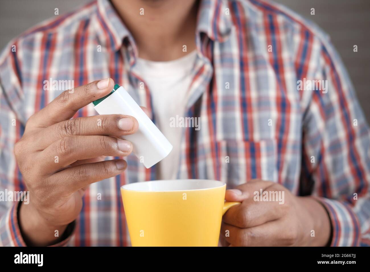 young man putting artificial sweetener in tea, Stock Photo