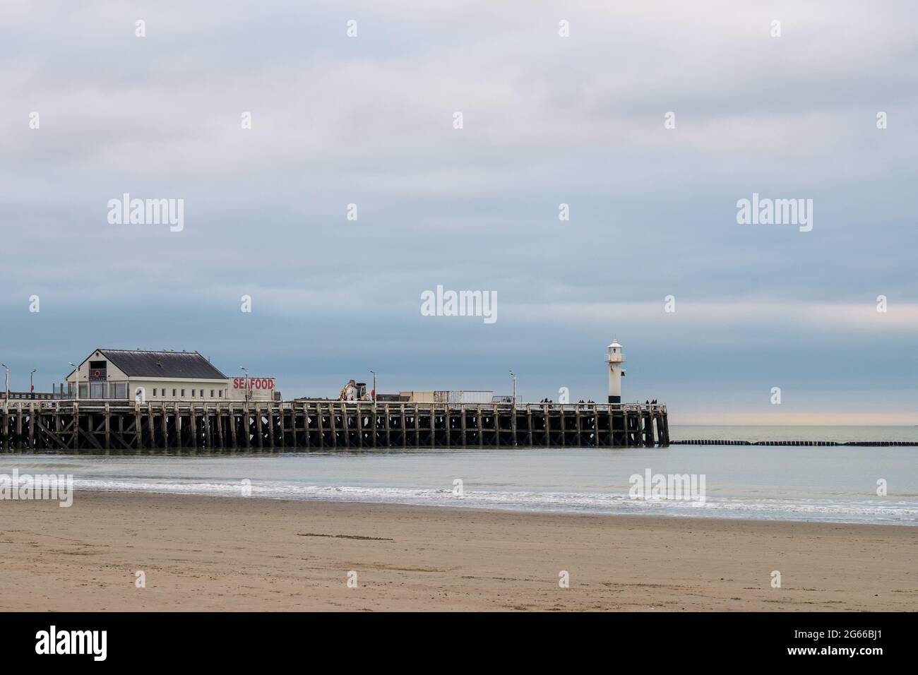 The beach of Blankenberge (Belgium) with old wooden pier and lighthouse in the background. Stock Photo